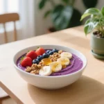 Are Acai Bowls Healthy? Vibrant purple acai bowl topped with fresh berries, banana, granola and honey on wooden table